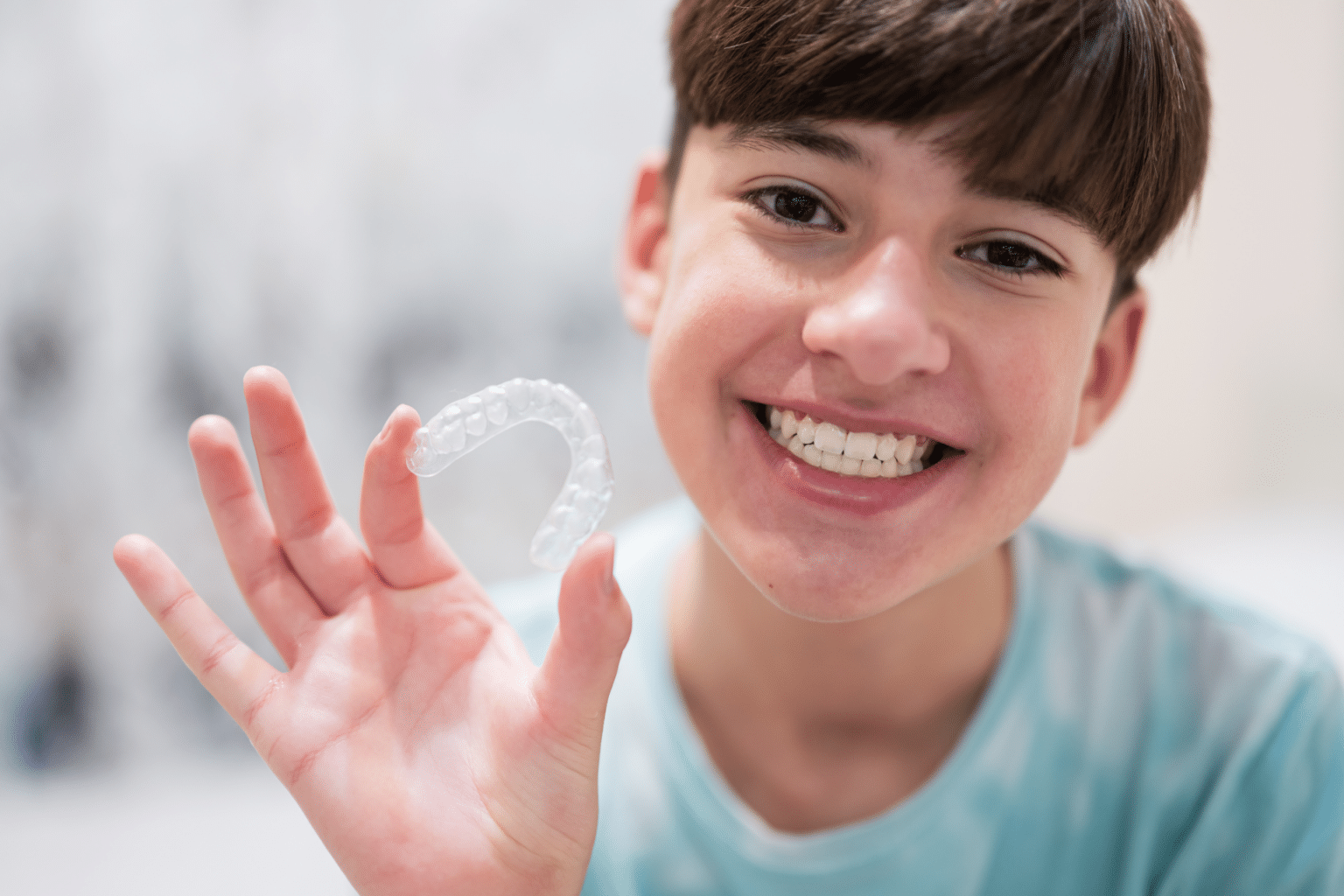 Teen holding clear aligners for Invisalign treatment