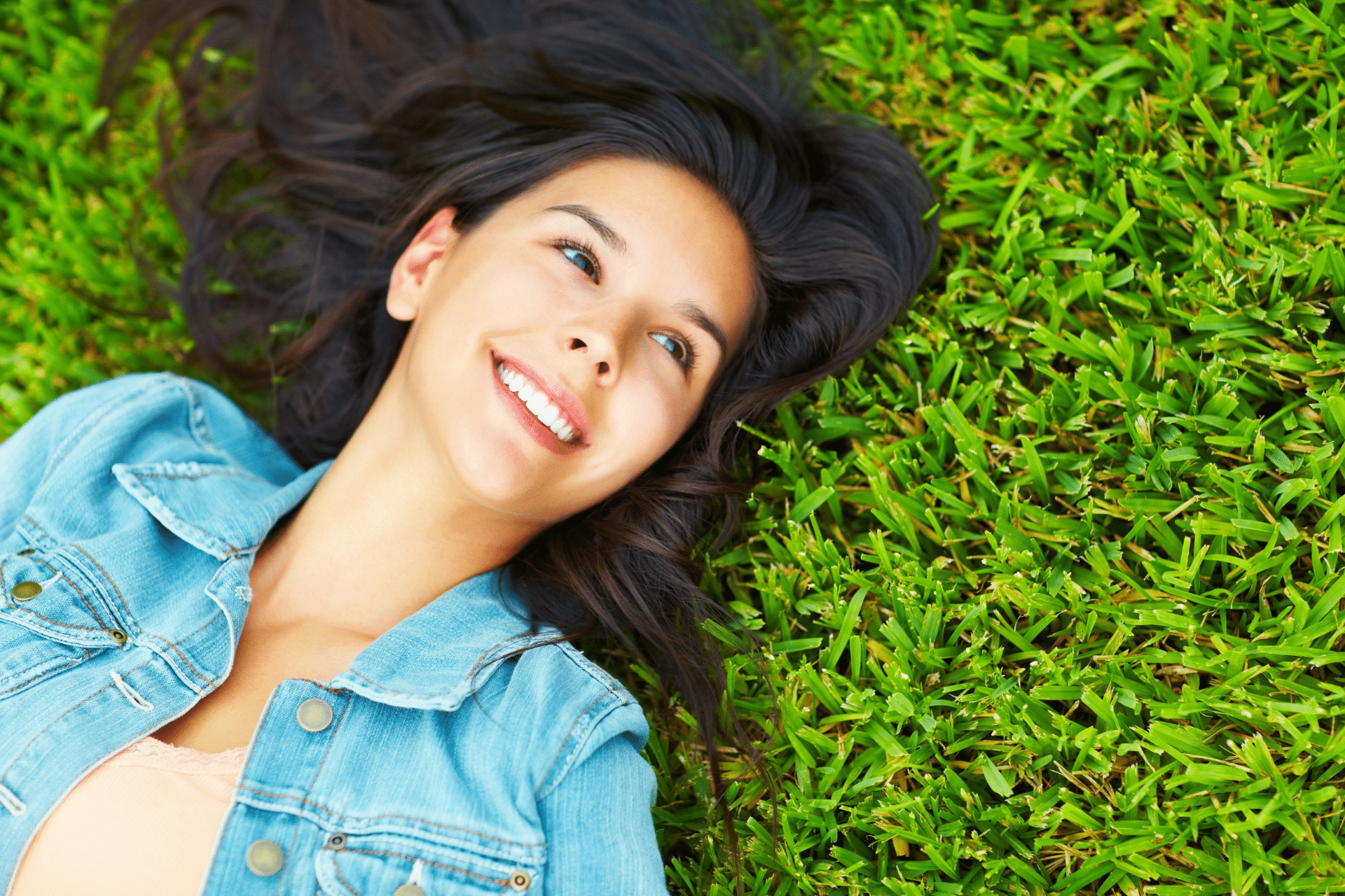 Smiling woman lying on green grass
