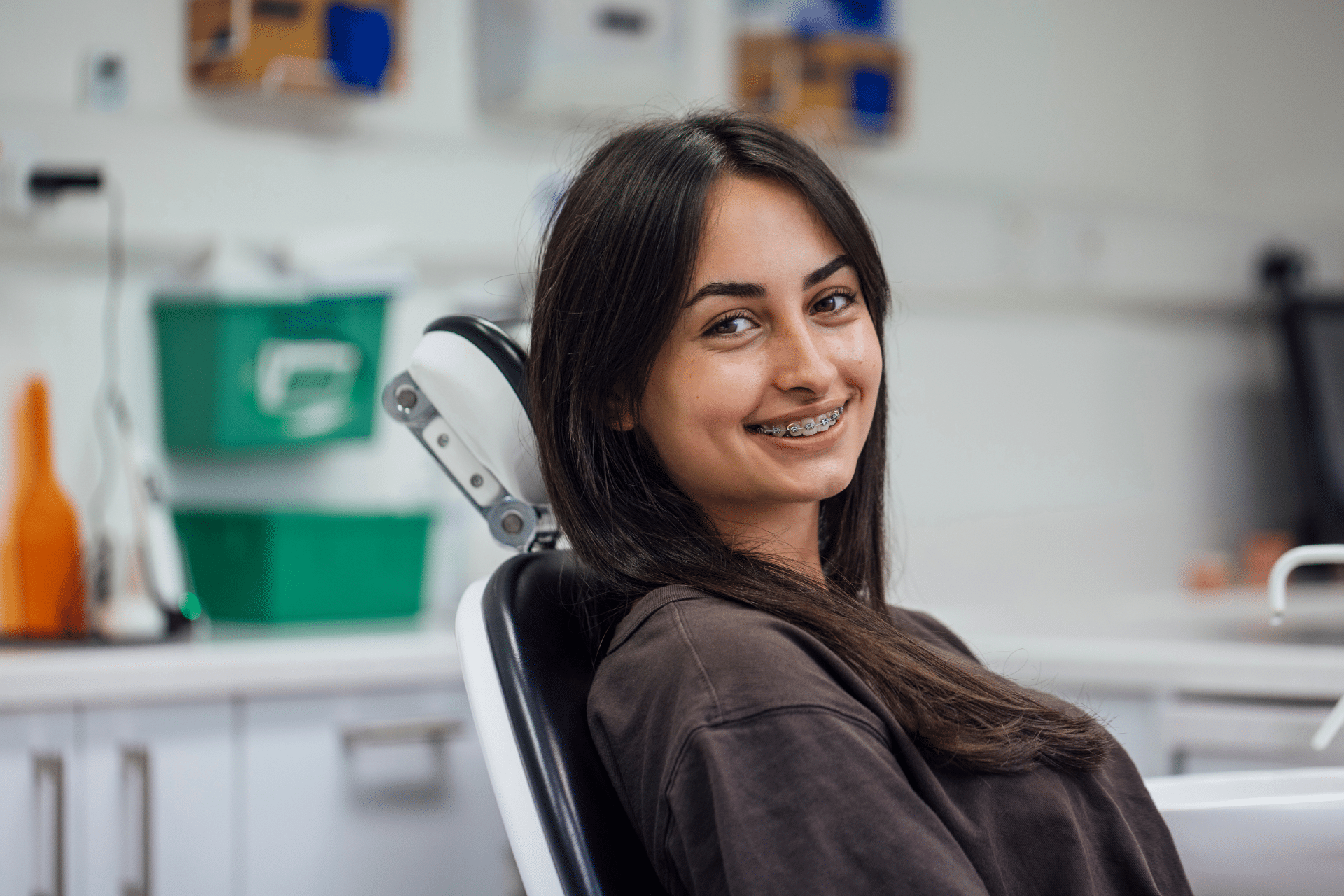 Patient with braces smiling while seated in an orthodontic treatment chair